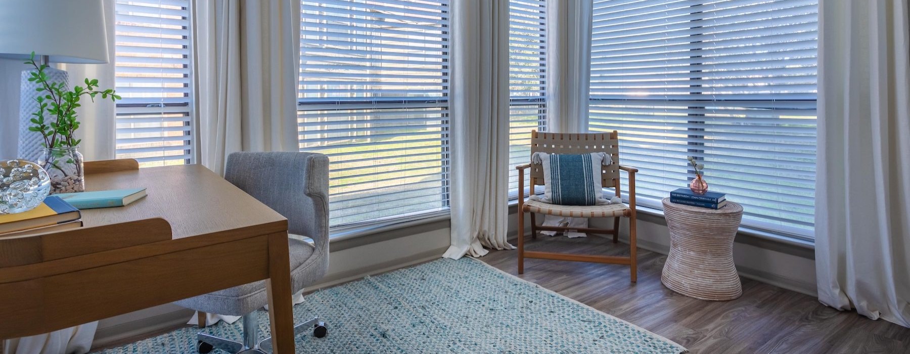 a room with a table, chairs and a window with curtains