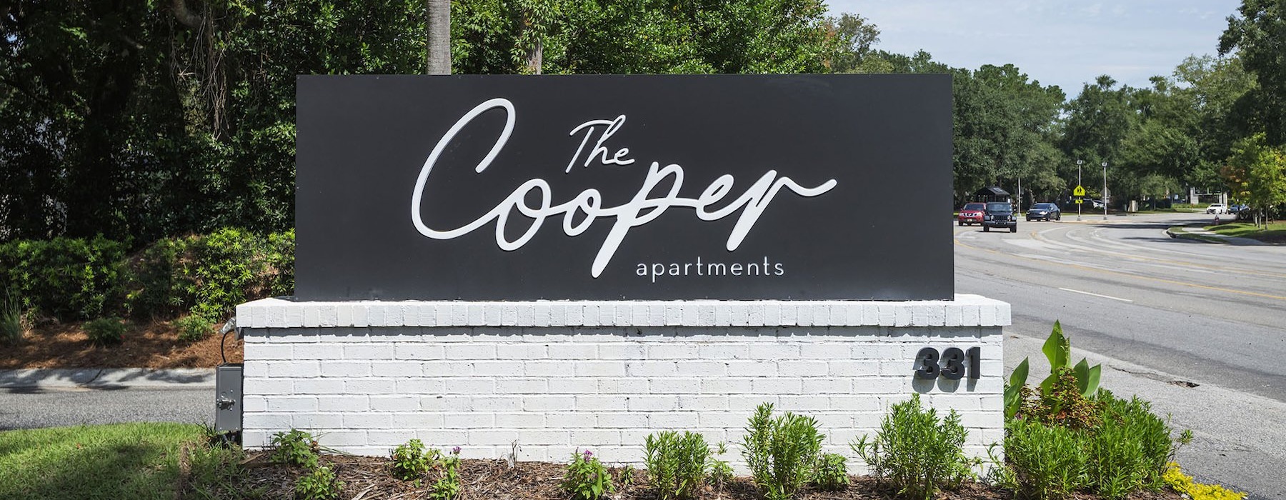 a sign for a property in a flower bed